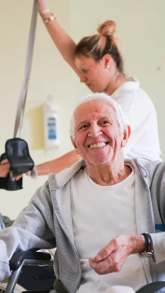 A smiling patient with his therapist in the therapy hall