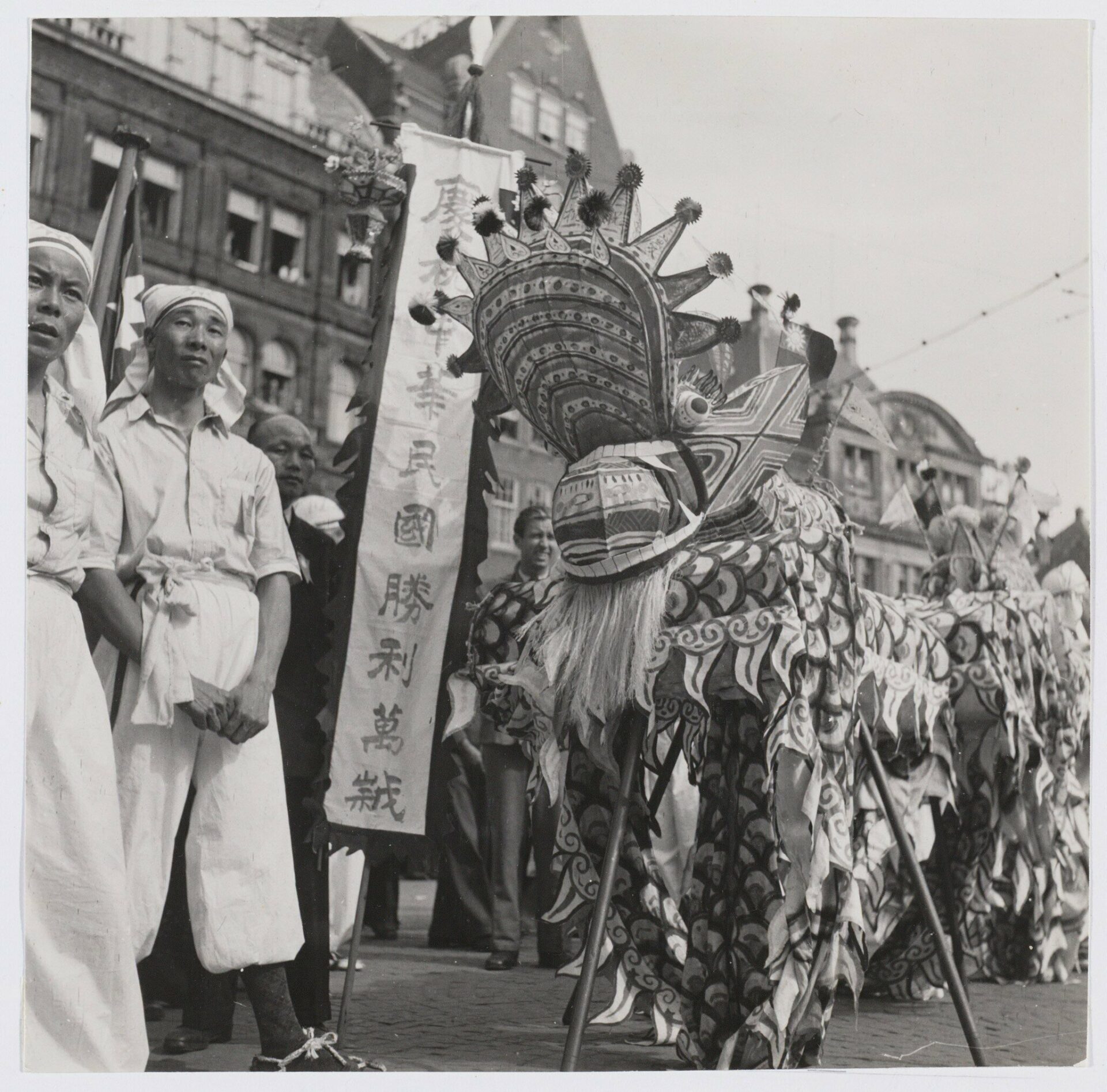 Chinese leeuwendans met een spandoek tijdens het bevrijdingsfeest in Amsterdam, september 1945