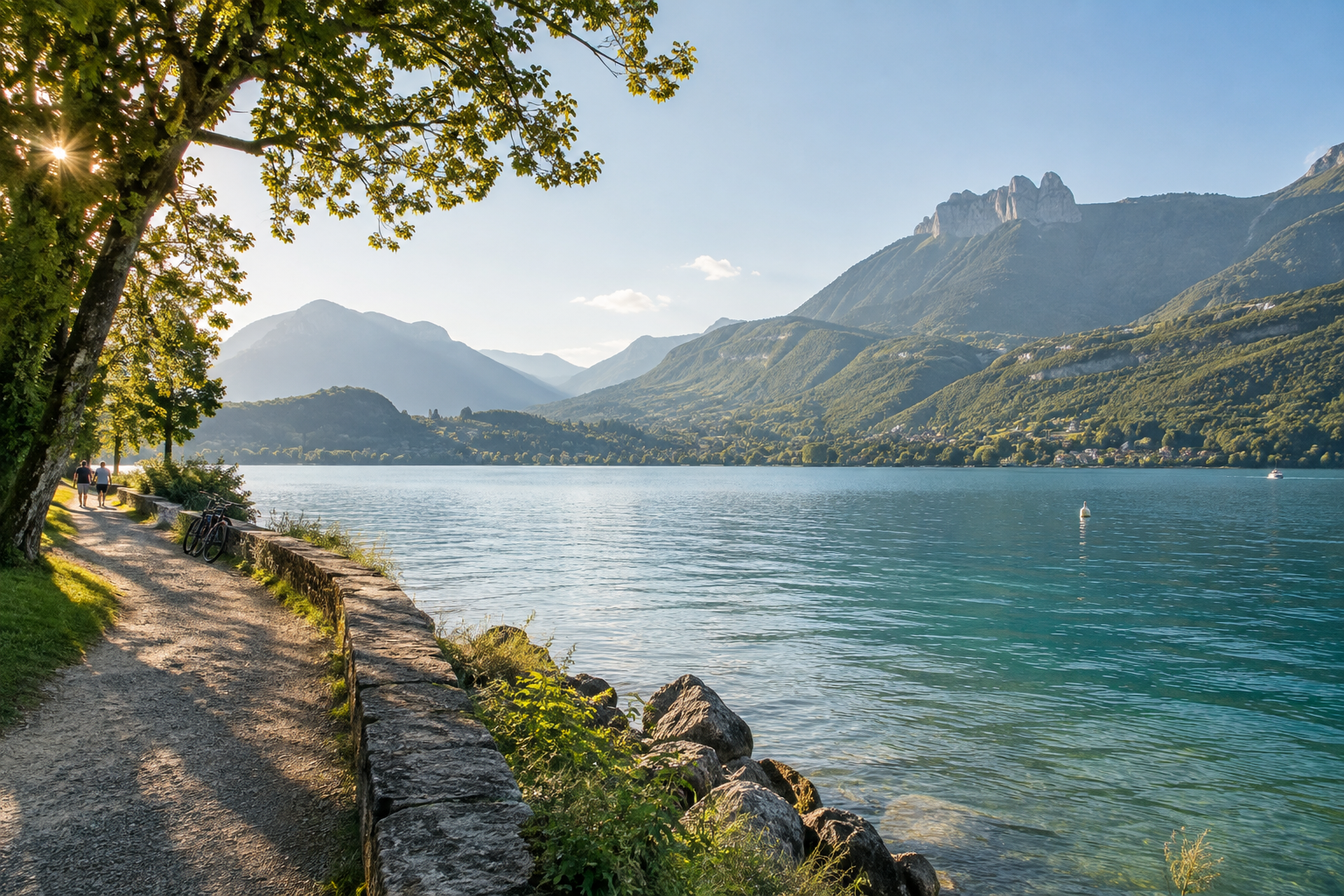 Promenade paisible au bord du lac d’Annecy avec vélos, montagnes et silhouettes discrètes.