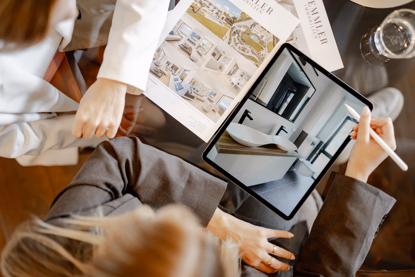 Minimalist office with white desk, chair, plants, and Kemmler Immobilien logo on wall.