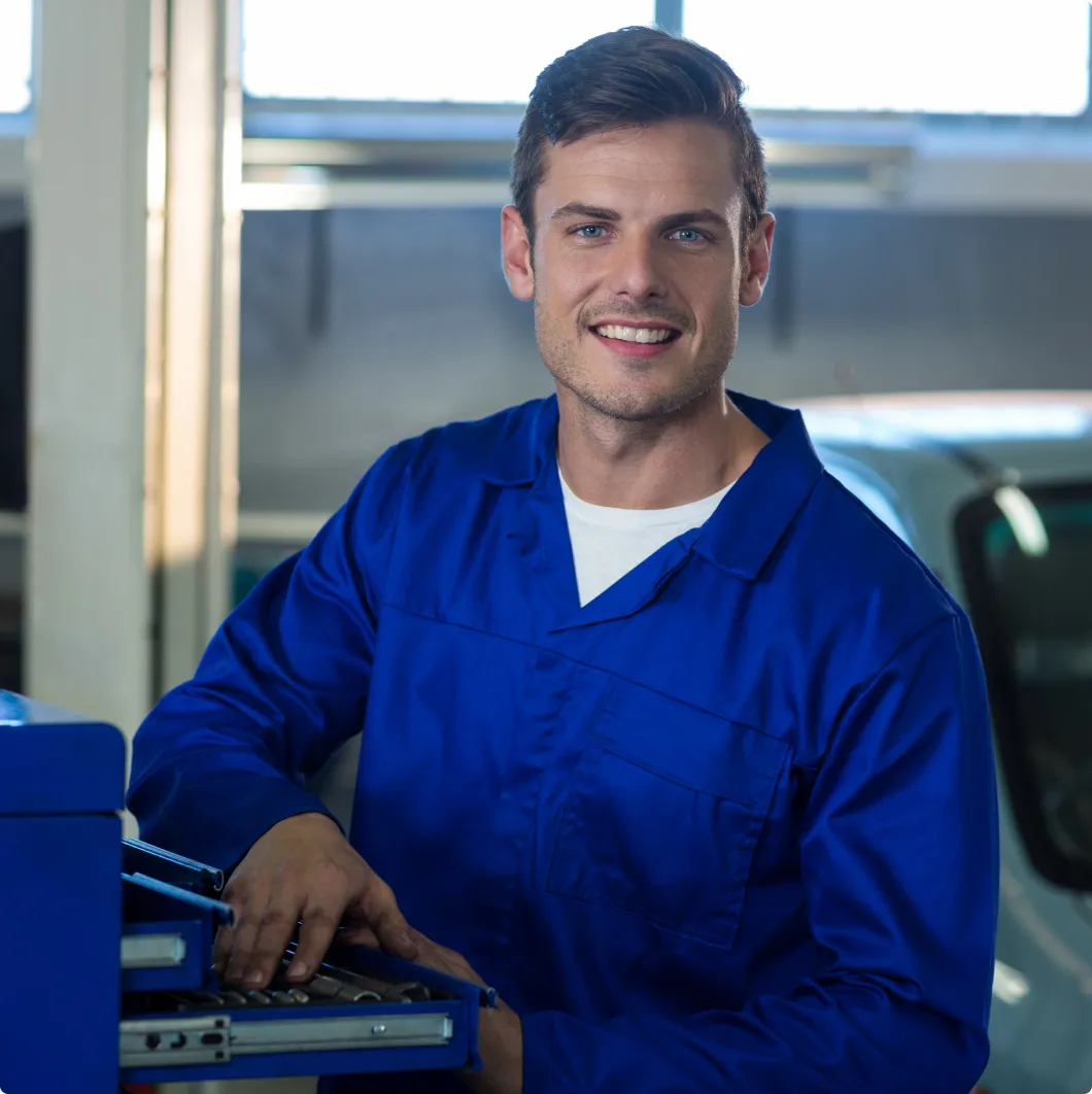Smiling mechanic by a toolbox
