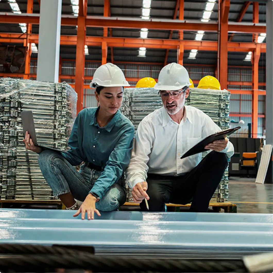Two workers with a laptop by steel materials