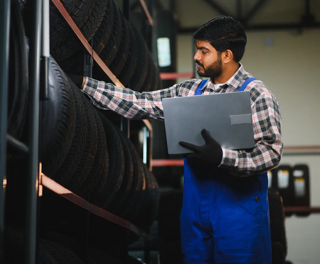 Man using a laptop by stacked tyres