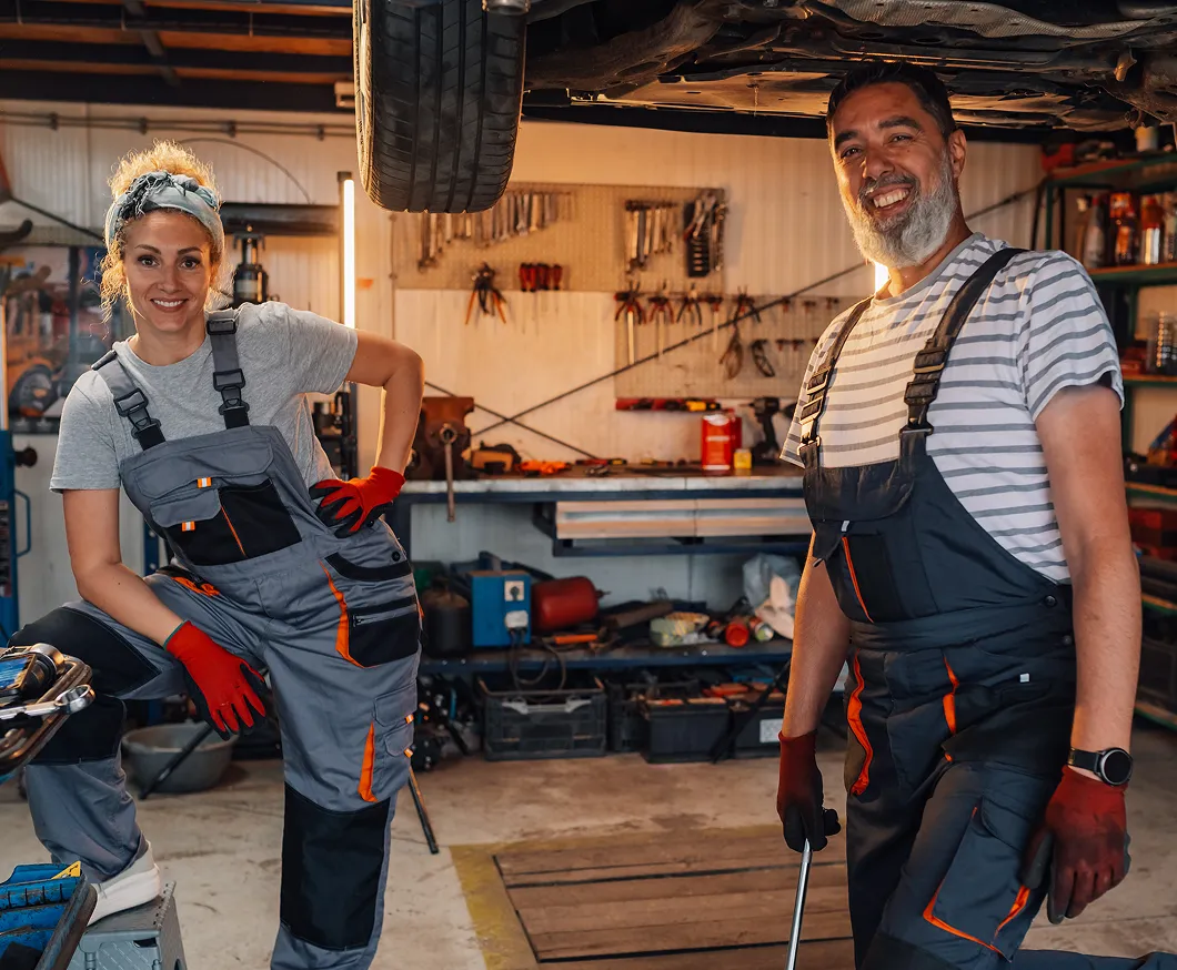 Two smiling mechanics in a workshop