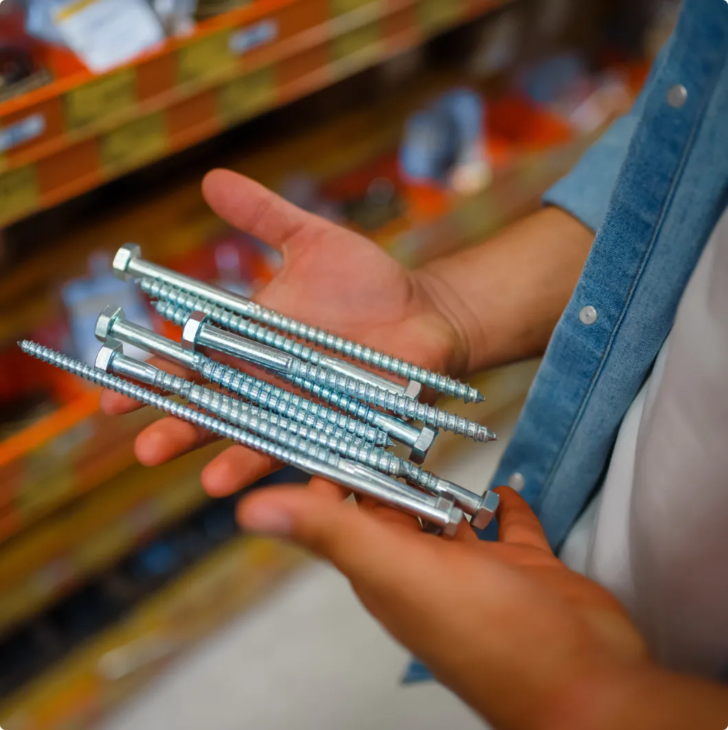 Hand holding screws by a store shelf