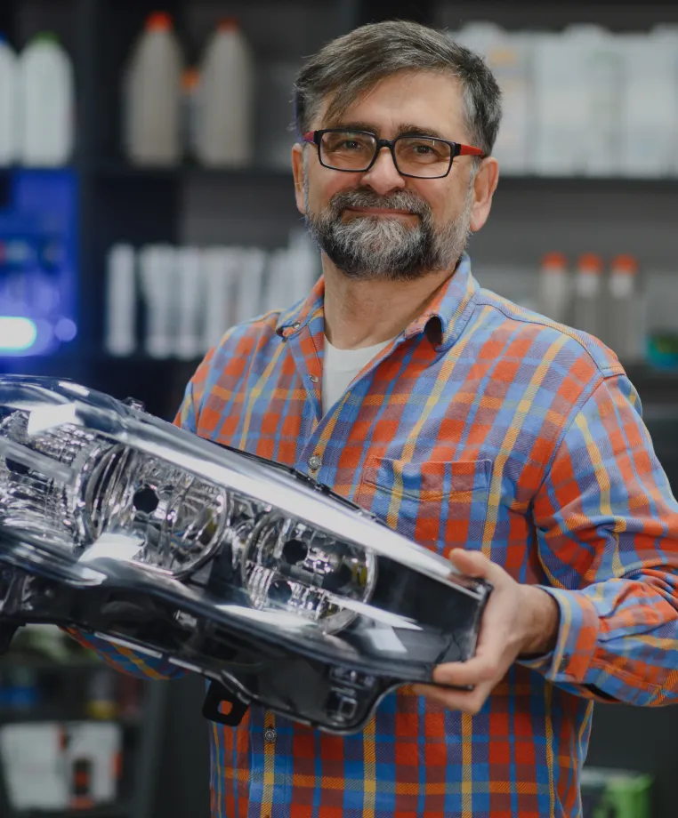 Man holding a car headlight in an auto parts shop