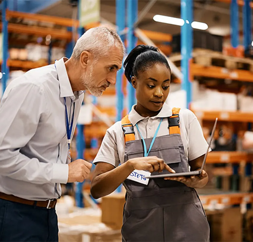 Colleague showing a tablet to a trainee in a warehouse