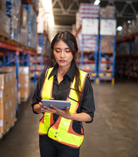 Woman in hi-vis holding a tablet in a warehouse