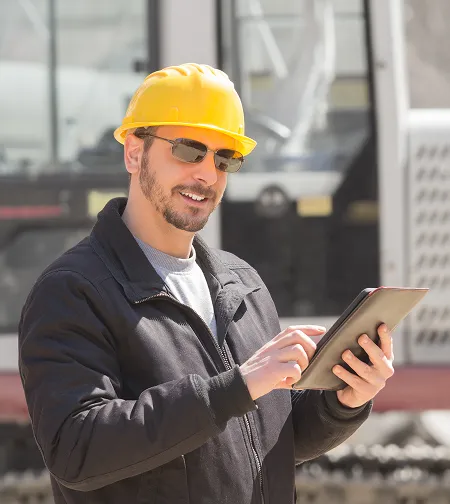 Worker in a hard hat using a tablet in a workshop