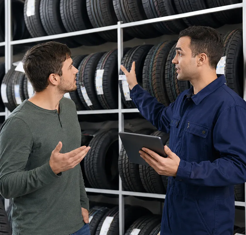 Two men discussing tyres with a tablet in a store