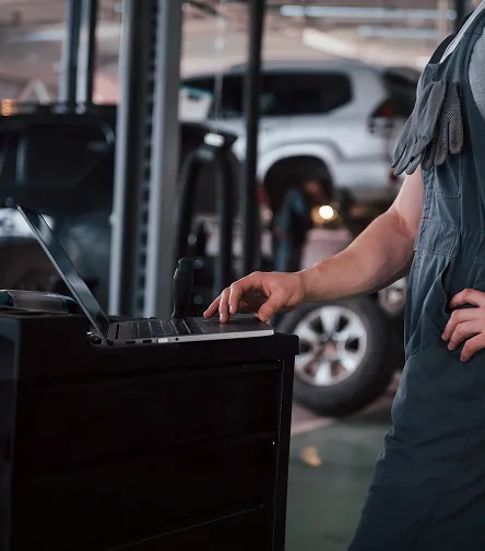 Mechanic using a laptop beside a car