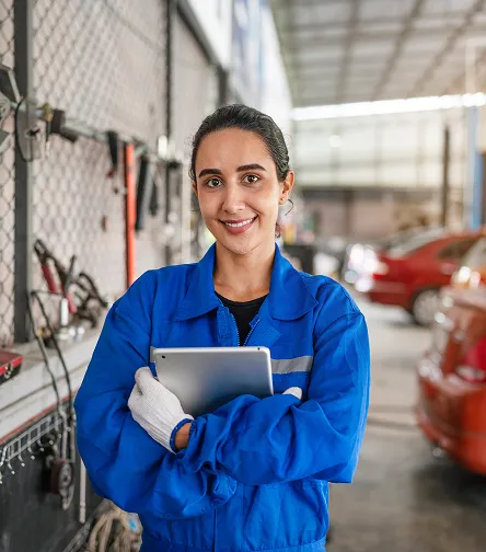 Smiling mechanic in overalls holding a tablet