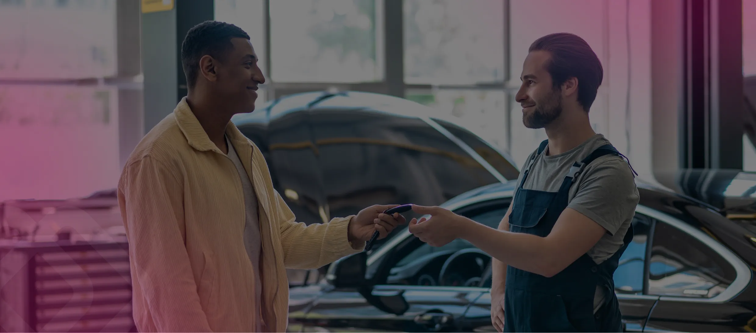 Two men shaking hands by a car