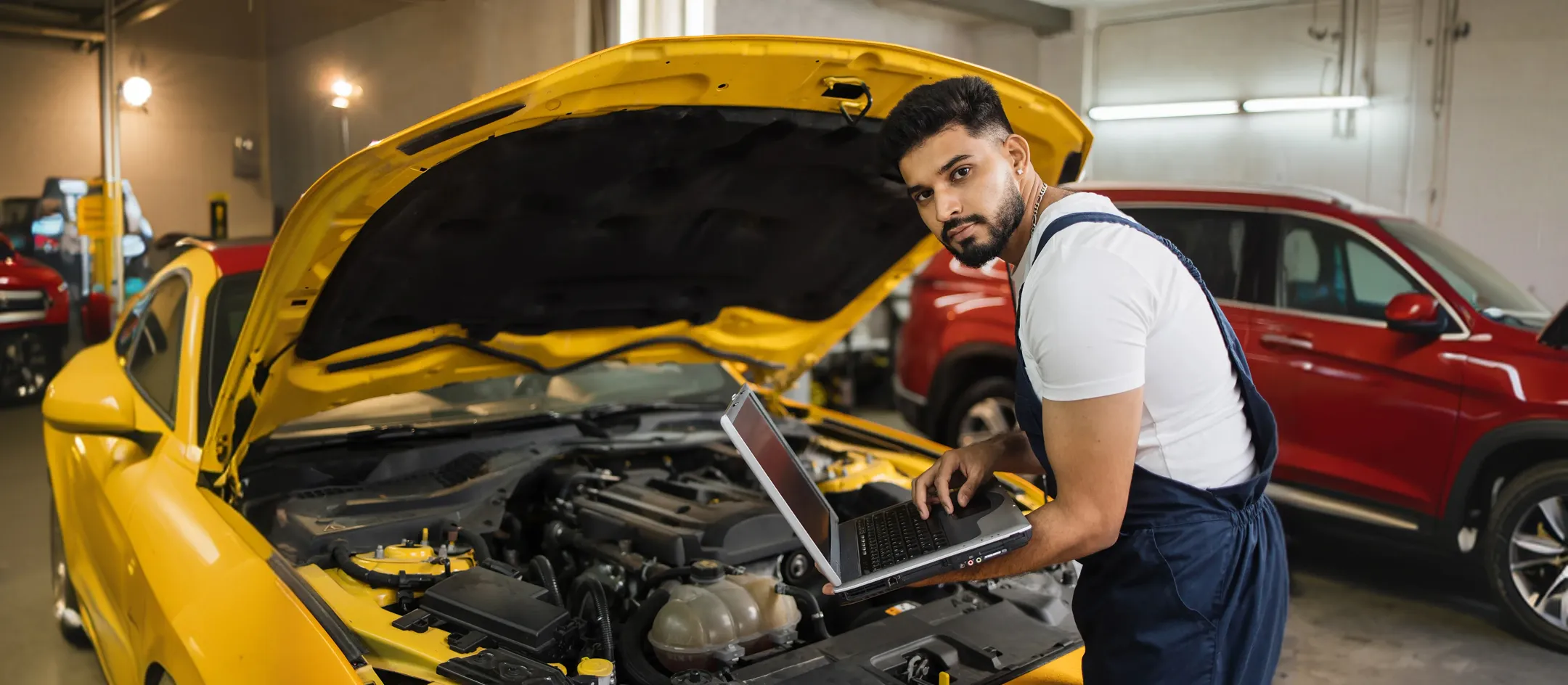 Mechanic using a laptop under a car bonnet