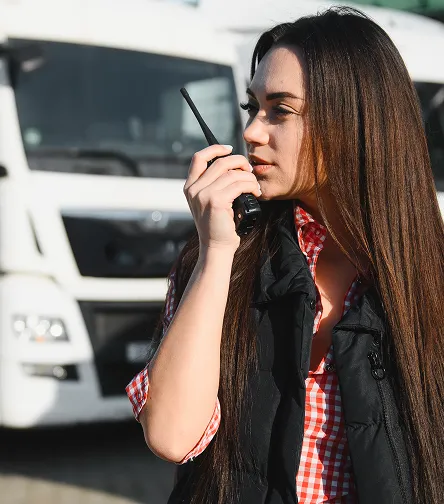 Woman using a two-way radio by a truck