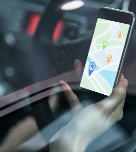 Hand holding a phone with a GPS map in a vehicle