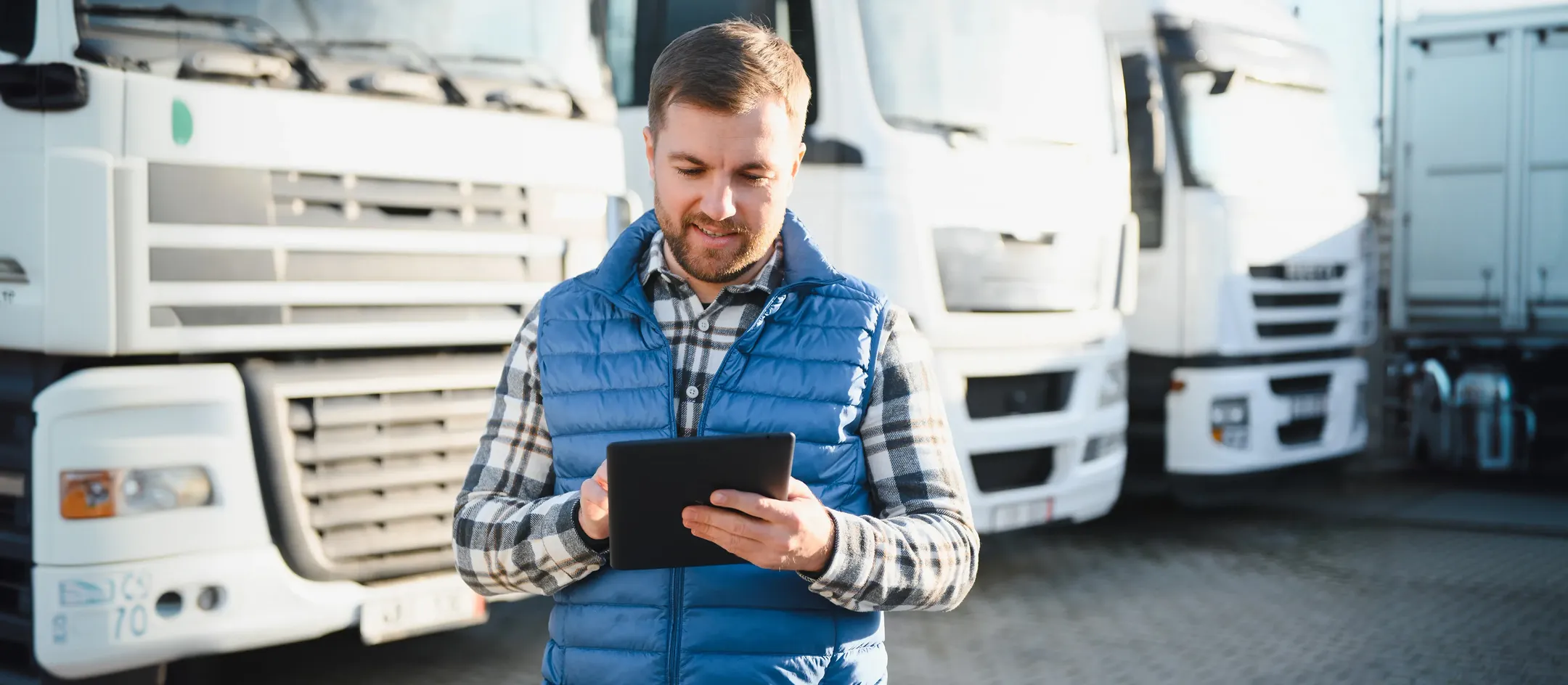Driver using a tablet in front of trucks