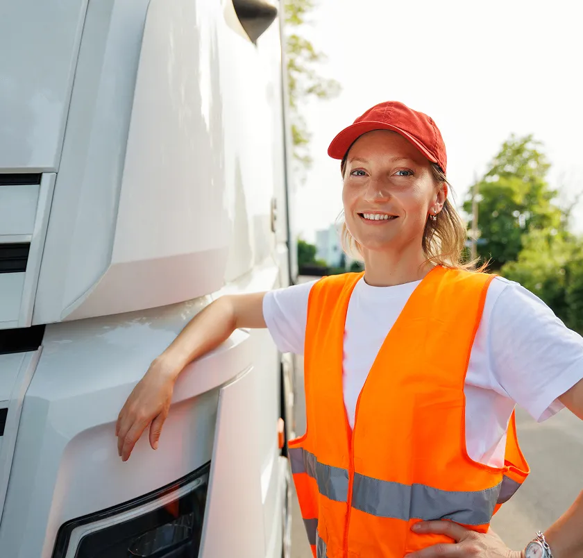 Smiling driver in hi-vis beside a truck cab