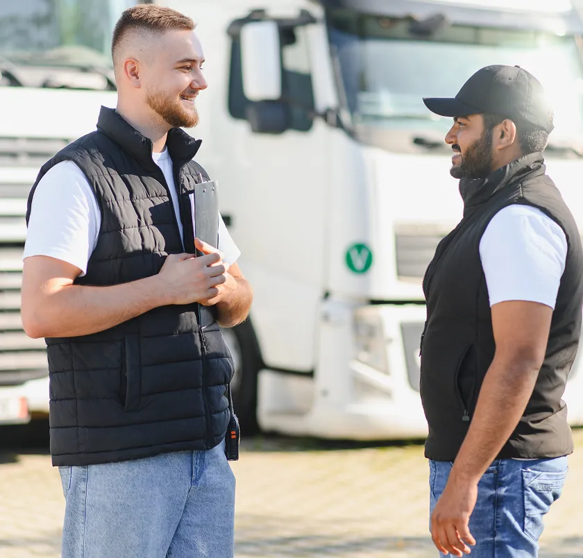 Two workers talking beside trucks