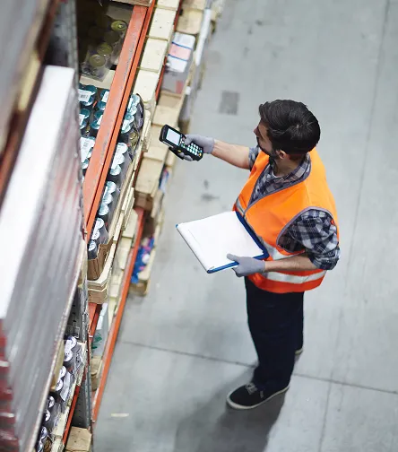 Worker with a scanner and clipboard by shelves