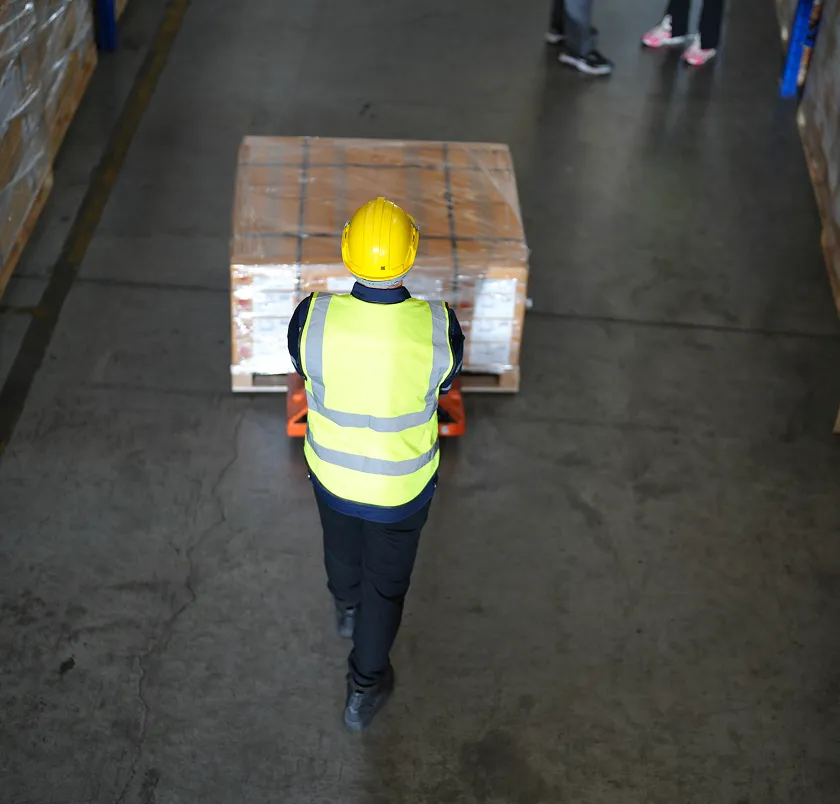 Overhead view of a worker moving a pallet truck in a warehouse