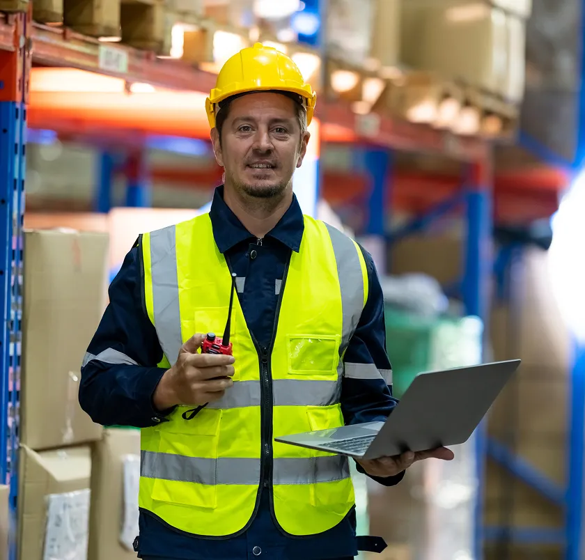 Warehouse manager in hi-vis holding a laptop