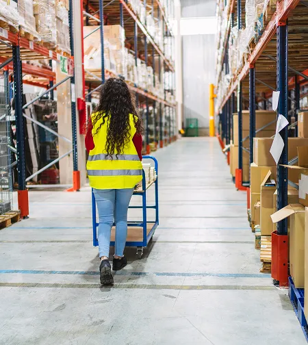 Worker pushing a trolley in a warehouse aisle