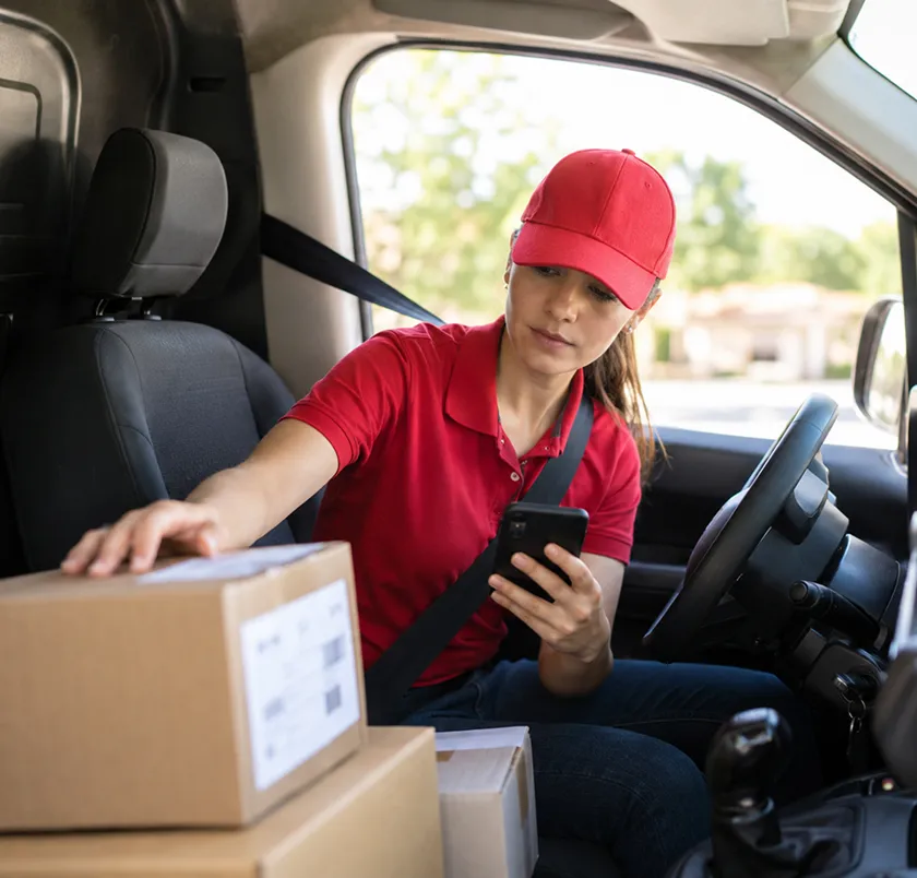 Delivery driver using a phone in a van with parcels