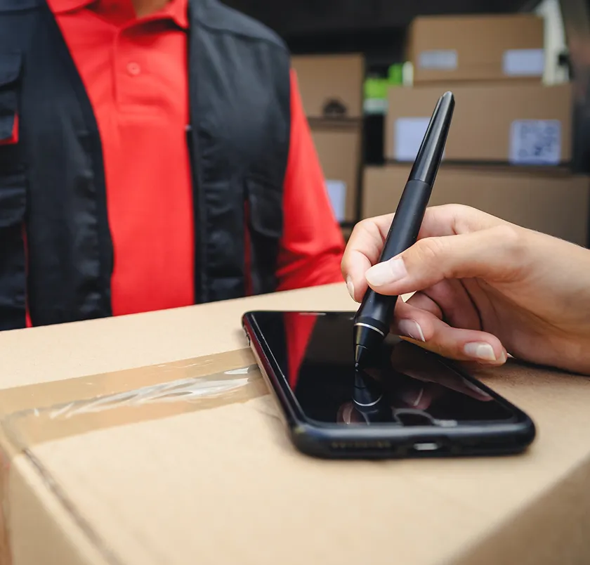 Hand using a stylus on a phone resting on a parcel