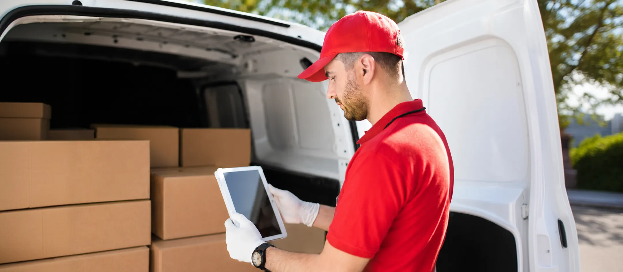 Delivery worker using a device at the back of a van