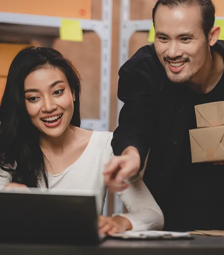 Colleagues with a laptop and parcel in a warehouse