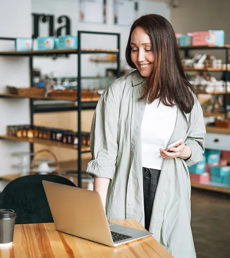Shop worker using a phone by store shelving