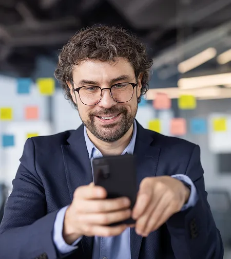 Smiling businessman using a phone in an office