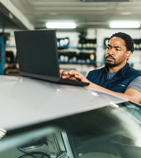 Man using a laptop resting on a car