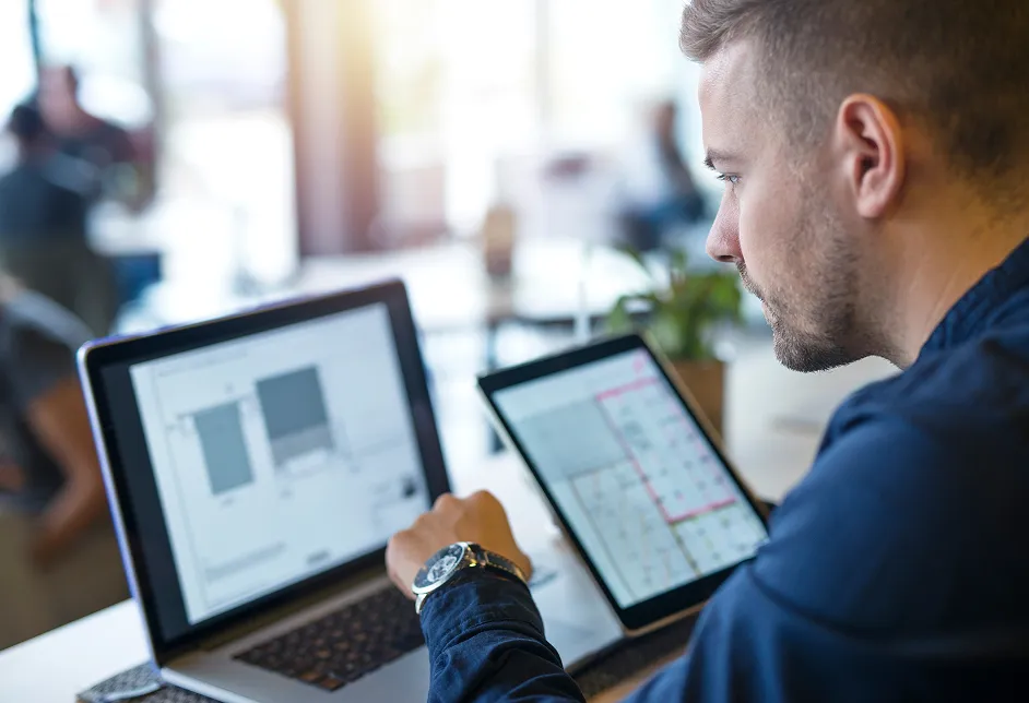 Man using a laptop and tablet at a desk