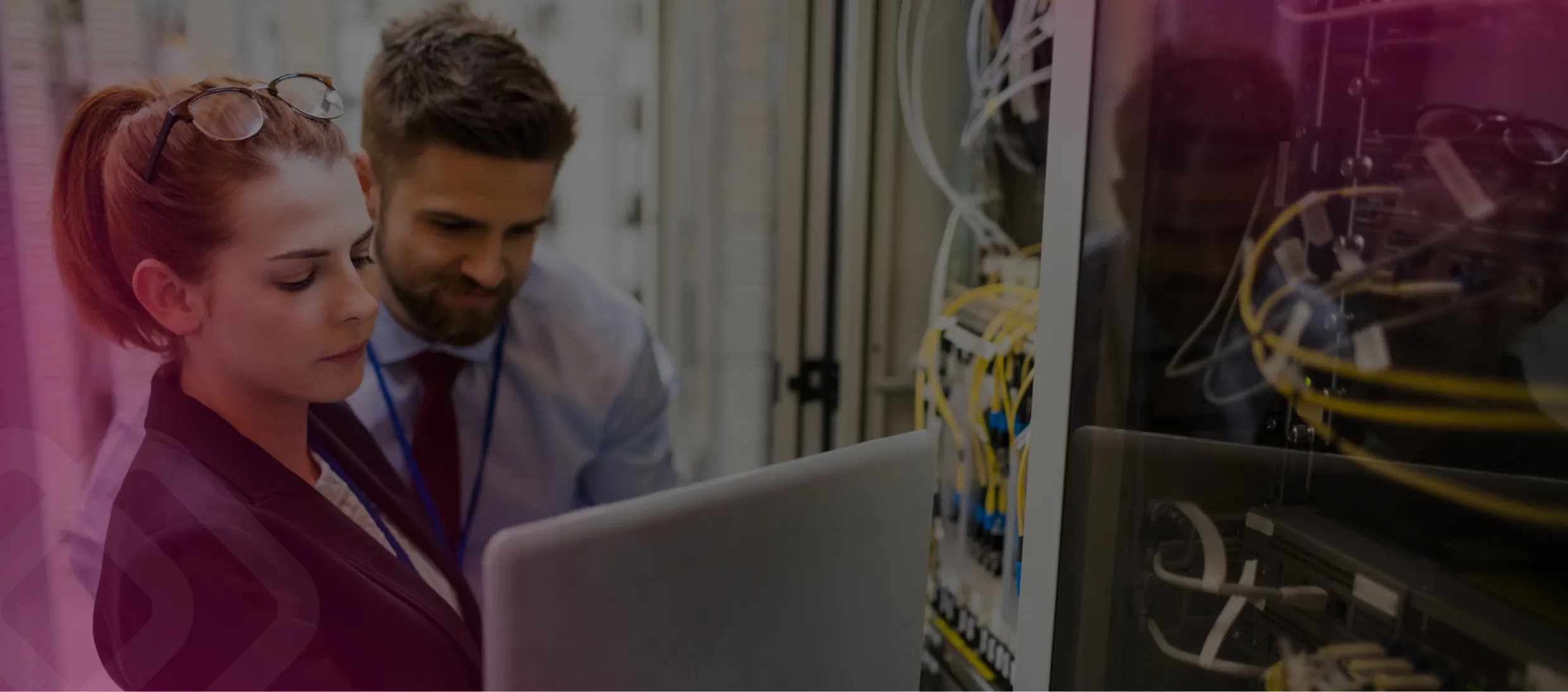 Two colleagues with a laptop by server wiring