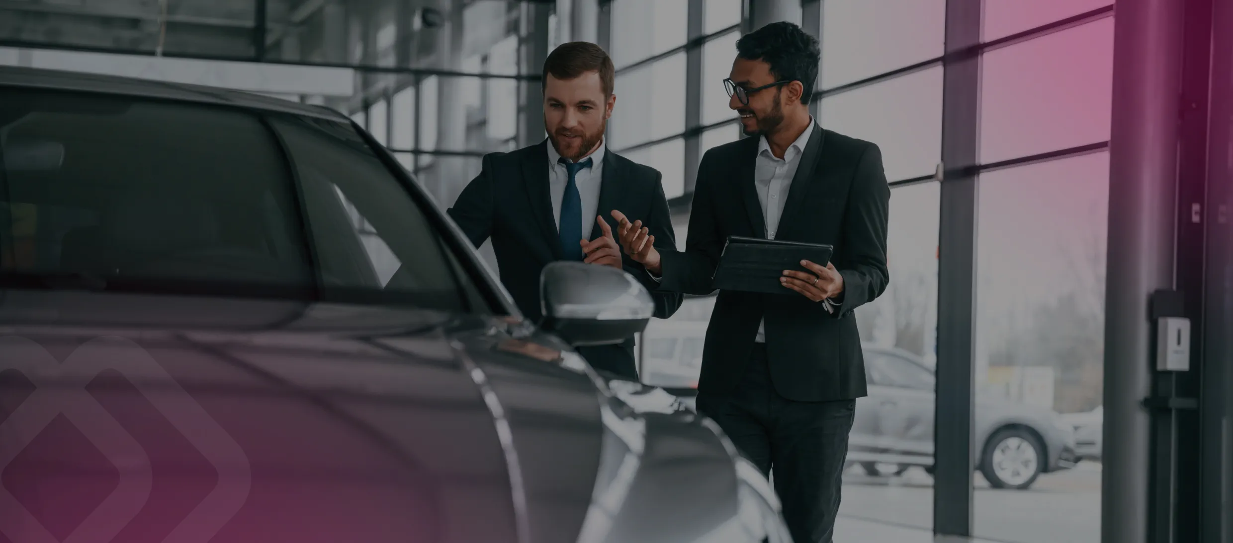 Colleagues talking by a car in a showroom