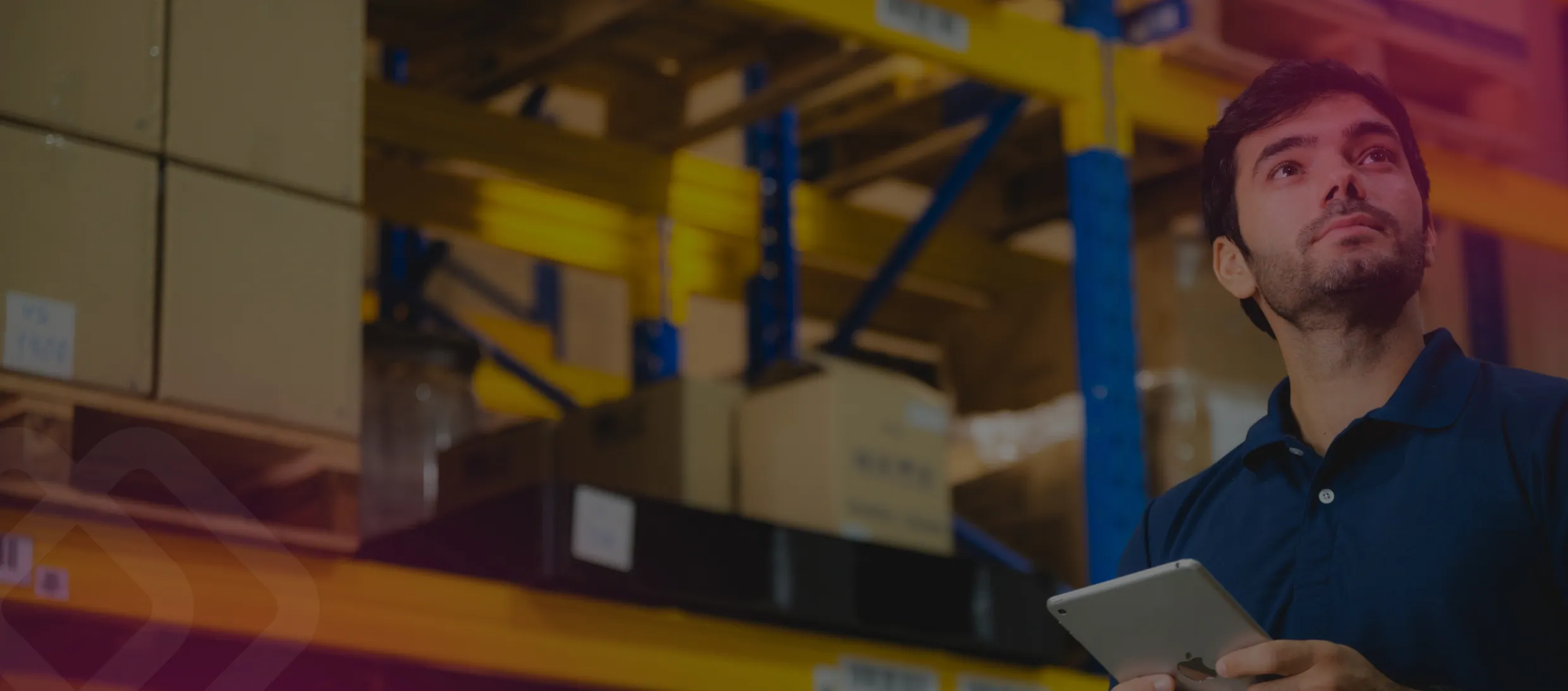 Man holding a tablet by warehouse shelving
