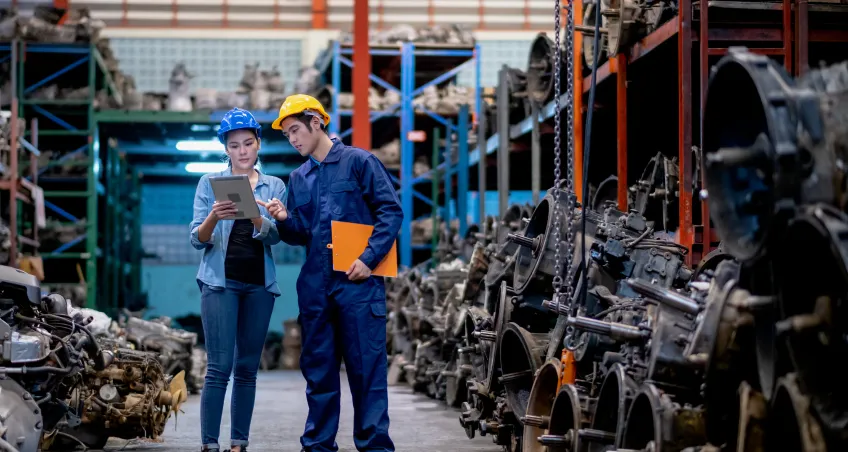 Two workers with a tablet in a parts warehouse