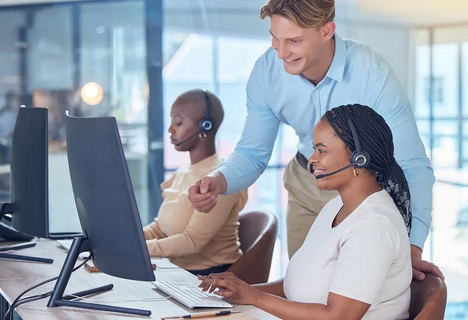 Manager helping a colleague at a computer