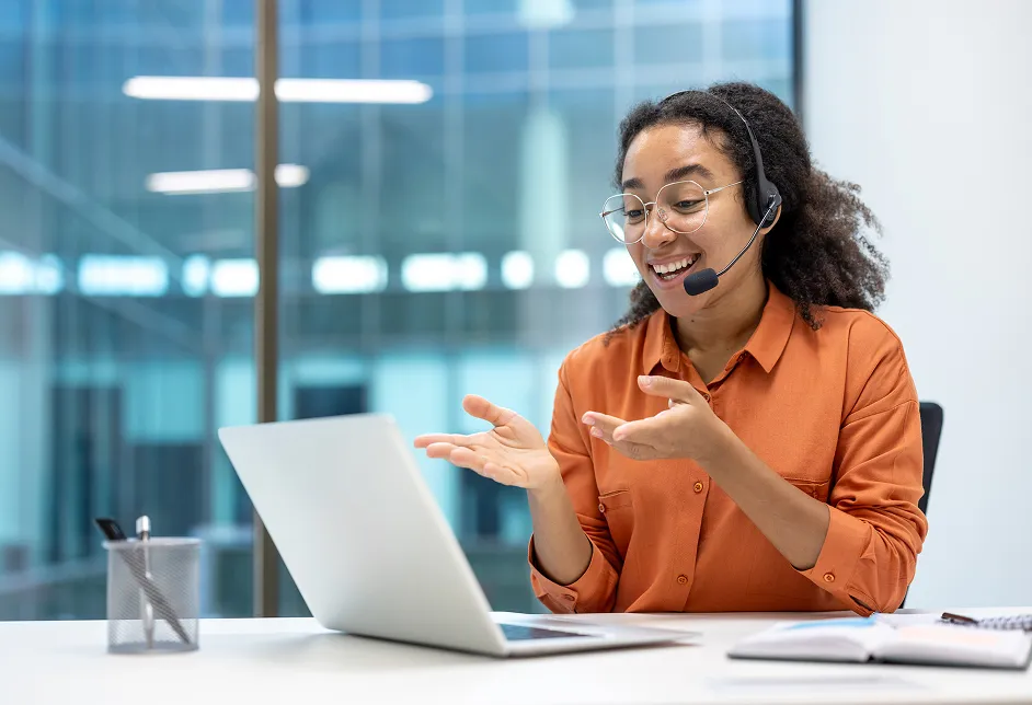 Smiling woman with a headset using a laptop