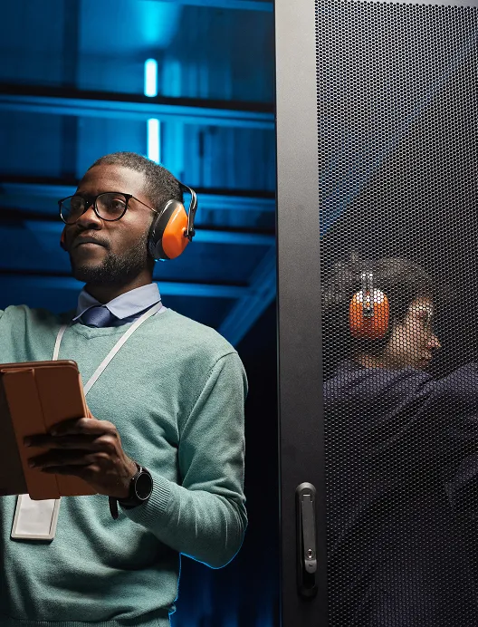 Man with headphones and a phone by a server rack