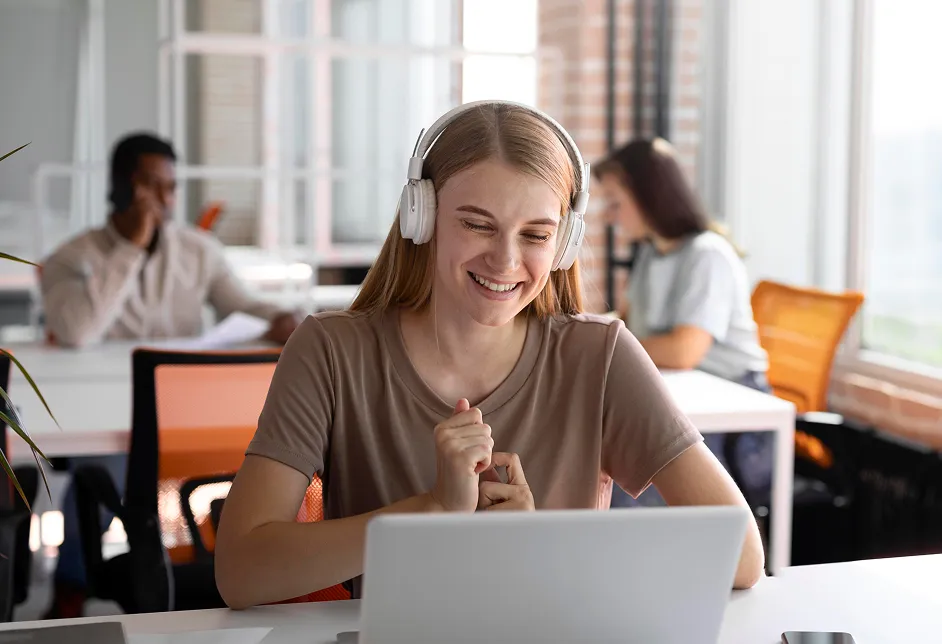 Smiling woman using a laptop with headphones