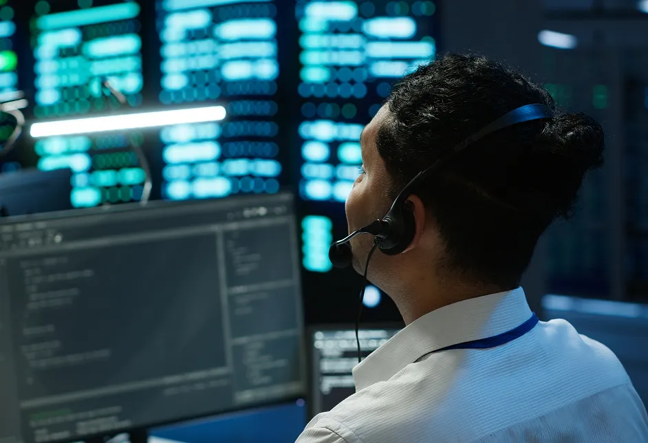 Man with a headset at monitors in a control room