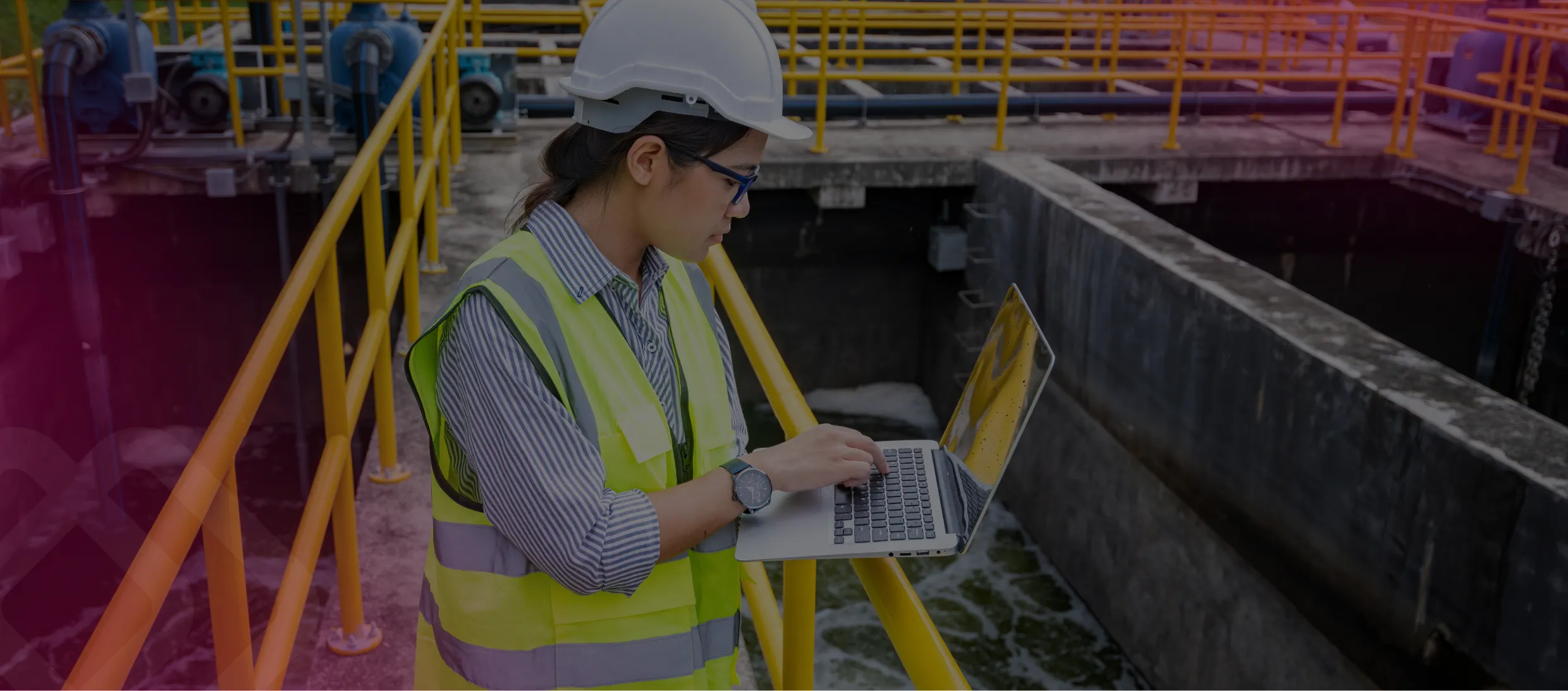 Worker in hi-vis using a laptop on a walkway