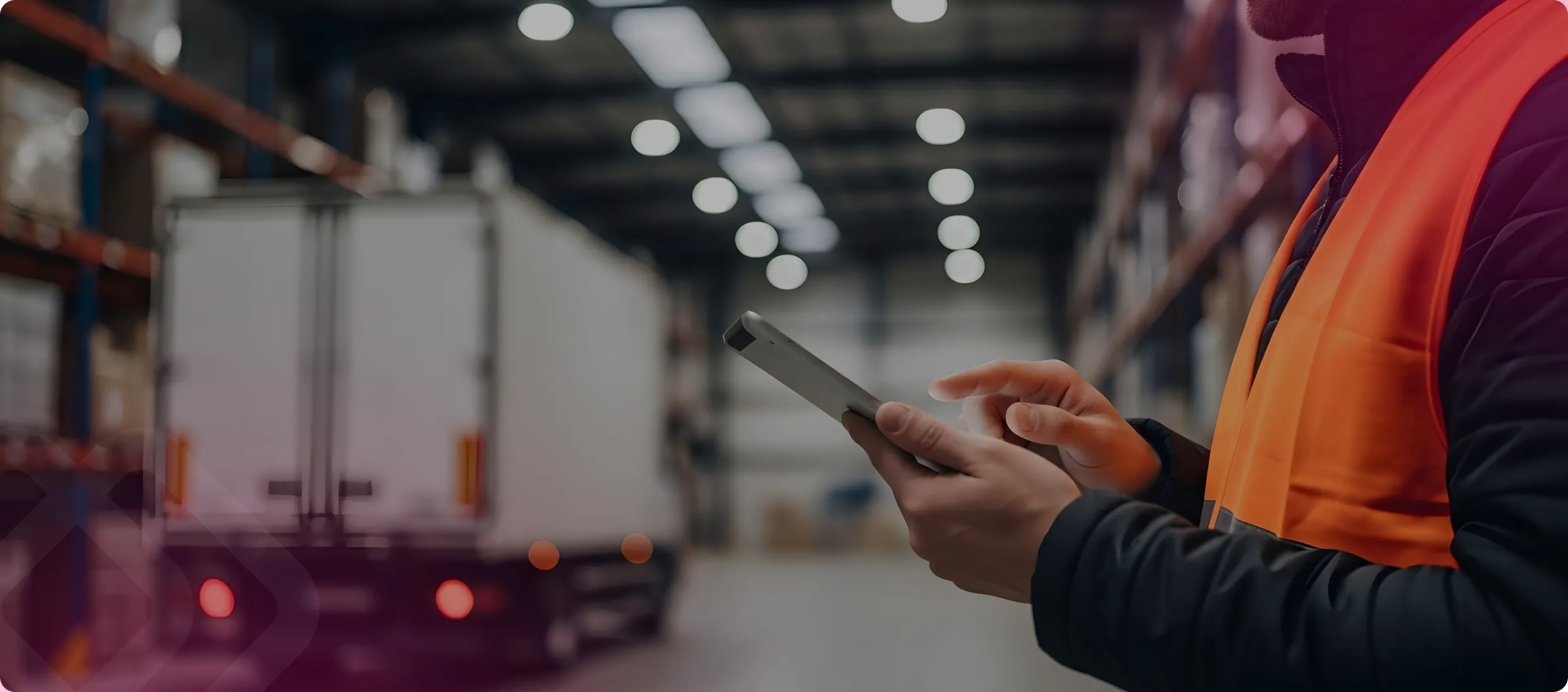 Worker in hi-vis using a tablet by a truck