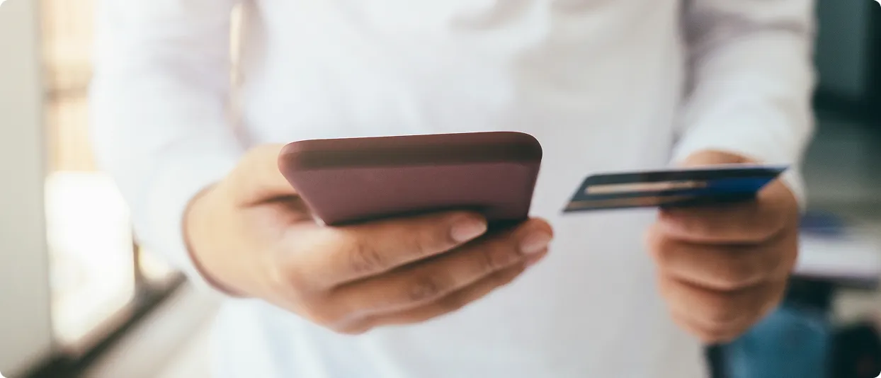 Person holding a phone and card to make a payment