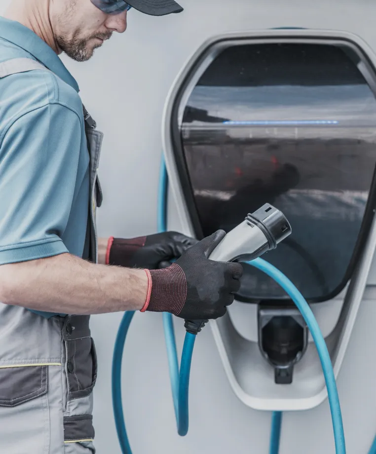 Worker plugging in an electric vehicle charger