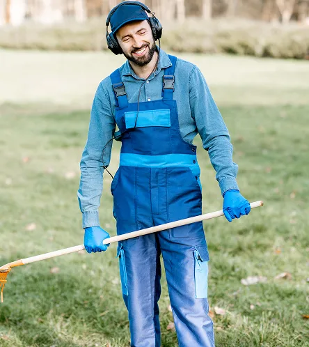 Grounds maintenance worker with a rake outdoors