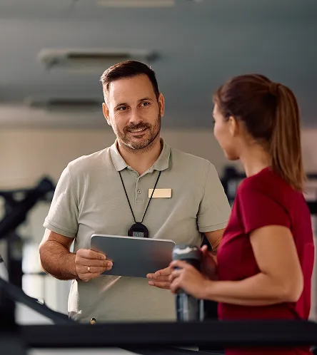 Gym staff member showing a tablet to a member